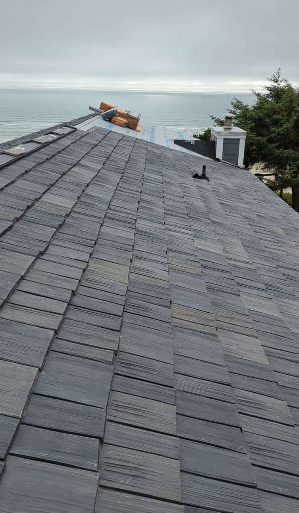 Slate roof overlooking a coastal view with construction materials visible.