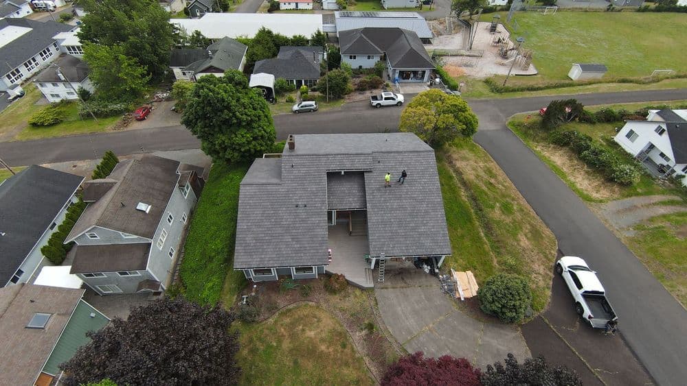 Aerial view of a house with a new roof being installed in a suburban neighborhood.